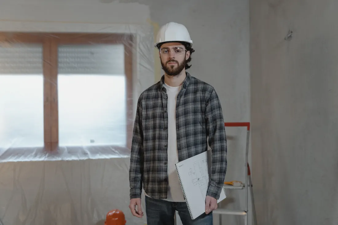 Wykonawca w kasku z projektem w ręku na remontowanym wnętrzu